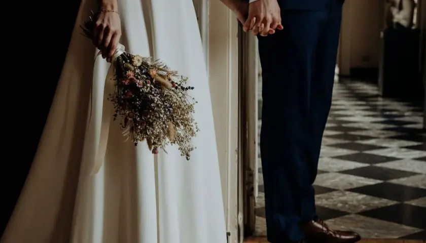 Novios tomados de la mano, ella con un ramo de flores secas, listos para su ceremonia civil.