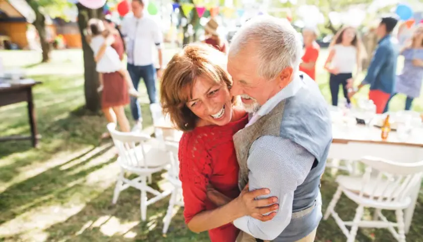 Pareja mayor bailando feliz en una fiesta al aire libre. 30 años de casados que significa: amor, complicidad y alegría compartida.