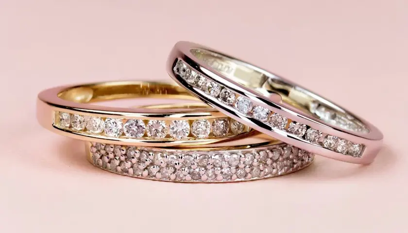 Tres anillos de diamantes apilados, uno de oro amarillo, otro de oro blanco y uno más con doble hilera de gemas. El anillo churumbela significado es de amor eterno.