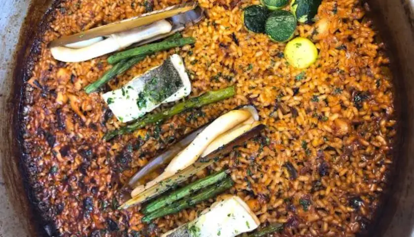 Paella con mariscos, espárragos y pescado. El fondo dorado y crujiente es el socarrat que es la parte más sabrosa.