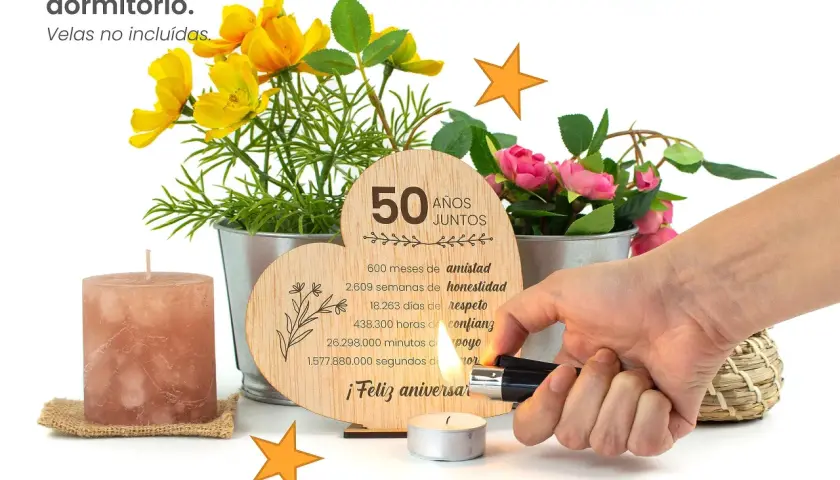 Corazón de madera con "50 Años Juntos" y detalles de flores. Un encendedor ilumina una vela, celebrando un feliz aniversario 50 años de casados.
