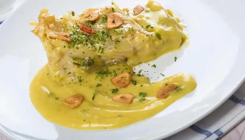 Bacalao en salsa pil pil, con láminas de ajo crujiente y perejil picado. Una deliciosa receta para disfrutar.