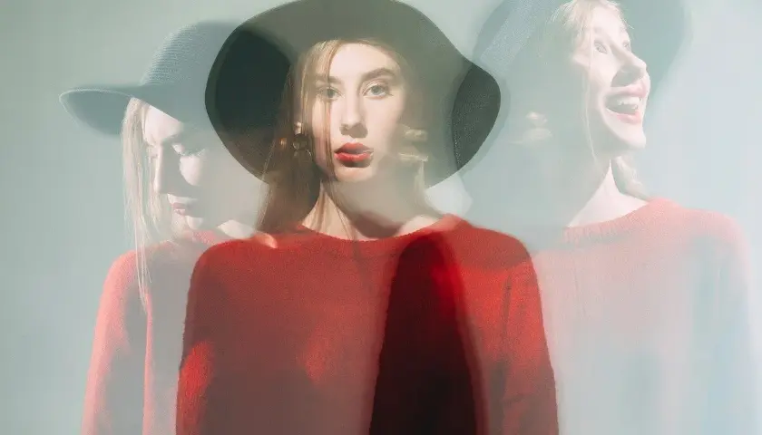 Mujer con sombrero y suéter rojo, capturada en múltiples exposiciones, reflejando su labilidad emocional.