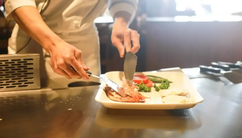 Chef emplata camarones y vegetales. El arte del show cooking, el significado de la pasión culinaria.