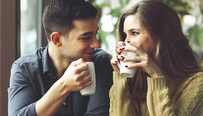 Una pareja joven comparte un café, mirándose con ternura. Un momento perfecto para pensar como decirle a alguien que te gusta.
