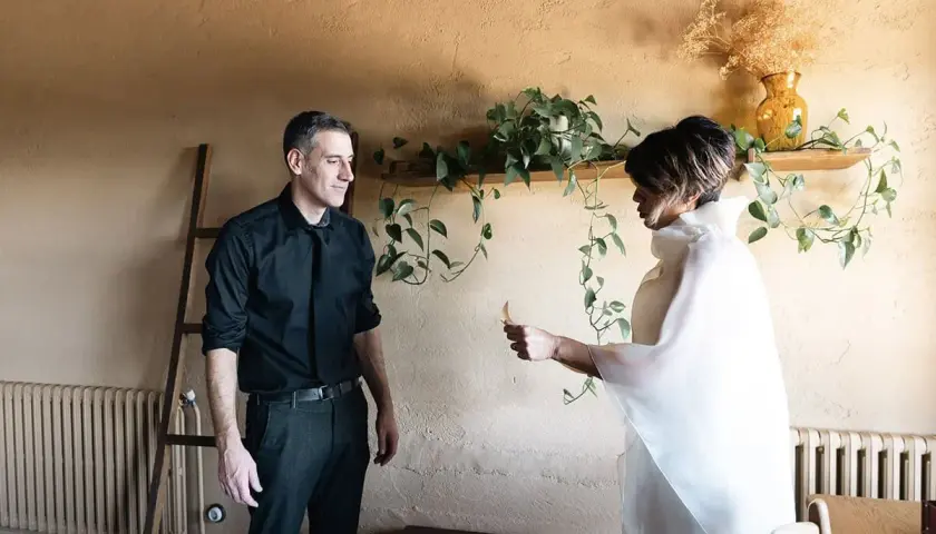 Pareja intercambiando un detalle, quizás una nota, como parte de sus ideas para aniversario. Él, de negro; ella, de blanco.