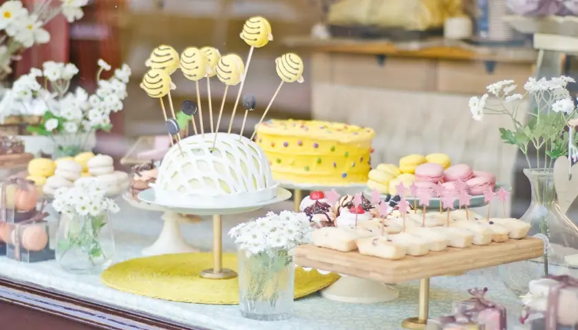 Deliciosa comida para revelación de género: pastel amarillo con lunares, macarons y bocadillos dulces.