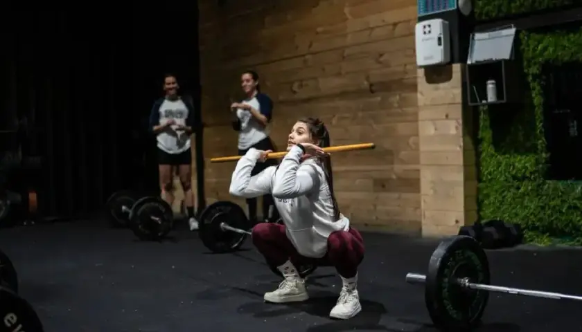 Mujeres entrenando en un gimnasio, demostrando los beneficios del crossfit con una barra.