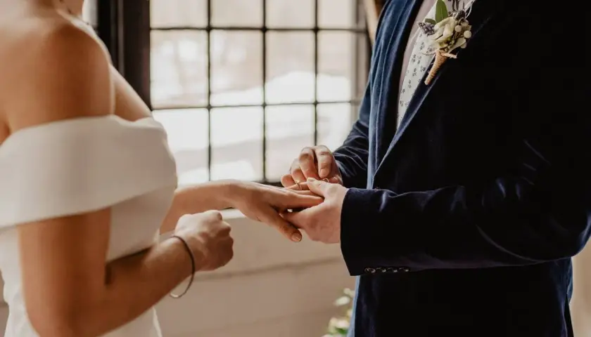 Novio pone anillo a novia. Un juez o funcionario civil es quien puede oficiar una boda civil.