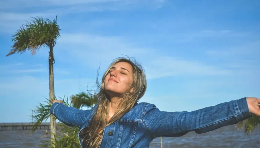 Mujer con brazos extendidos, disfrutando del aire libre, como si viviera una de las frases de Lao Tse sobre la libertad y la naturaleza.
