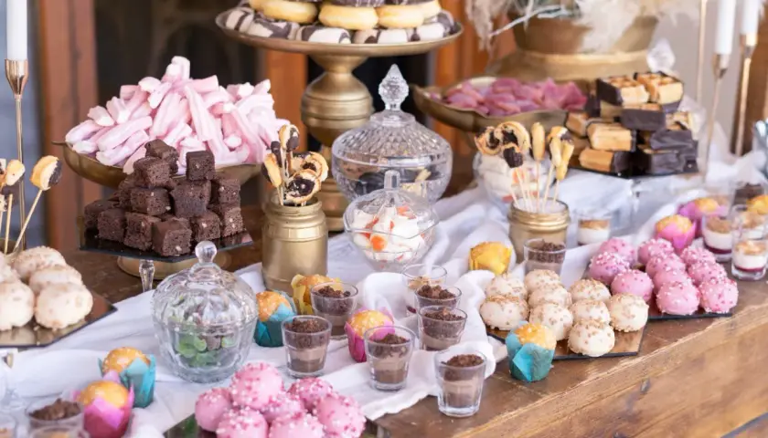 Mesa dulce casera para boda: brownies, malvaviscos rosas, donuts, pastelitos y más.