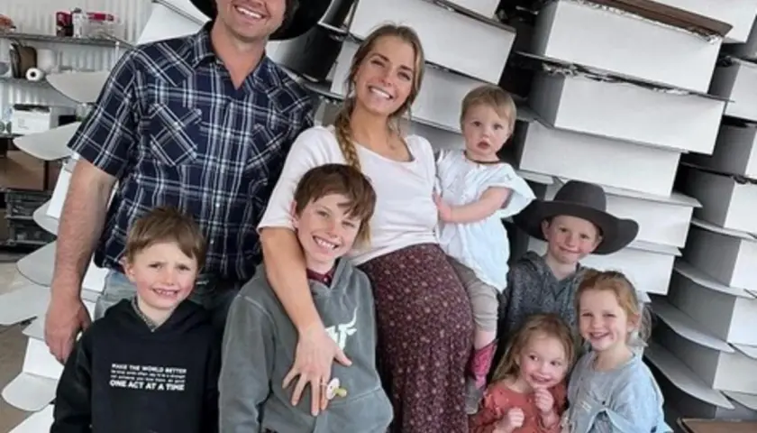 Familia feliz, estilo tradwife que es, posando con sus hijos frente a cajas apiladas.