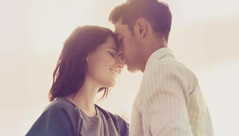 Parejas enamoradas, con sus frentes juntas y sonrisas tiernas, bajo la luz cálida del atardecer.