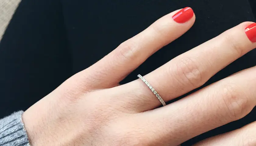 Anillo de diamantes finos, perfecto para frases para alianzas que sellan un amor eterno. Uñas rojas vibrantes.