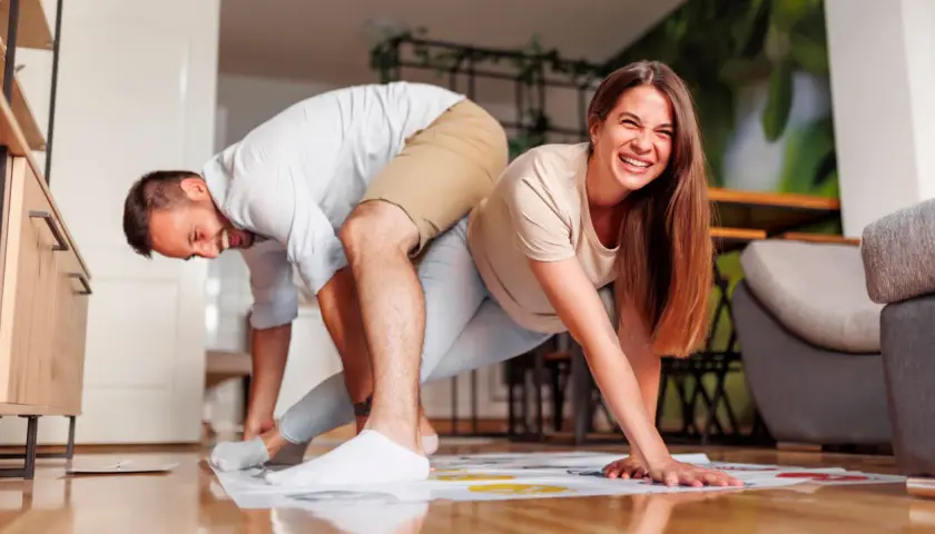 Pareja riendo mientras juega Twister, un divertido juego para jugar en pareja.