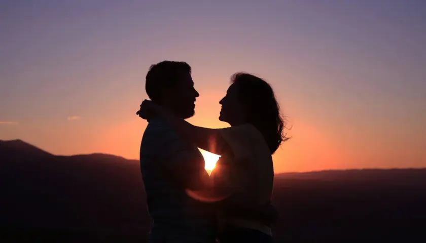 Siluetas de pareja abrazándose al atardecer. Su conexión irradia una profunda compatibilidad, como si fueran cáncer y cáncer, unidos por el amor.