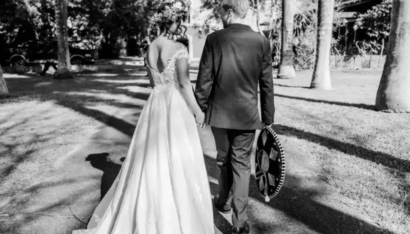 Novios caminando de la mano, ella con vestido de novia y él con traje y sombrero charro. Un recuerdo para todos los nombres de aniversarios de boda.