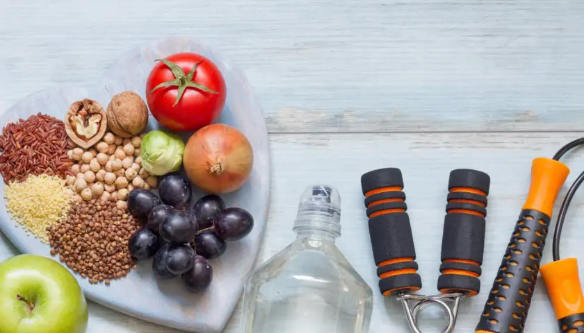 Alimentos saludables y equipo de ejercicio, como una cuerda de saltar y un expansor de mano, para tu motivación personal.