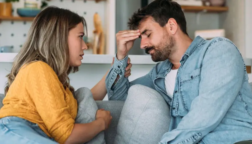 Mujer consuela a su pareja, con la mano en su frente, en un momento de tensión en su vida en pareja.