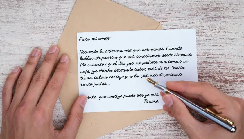 Una mano sostiene una pluma sobre una carta de amor para mi novio. El texto evoca el primer encuentro y la conexión instantánea.