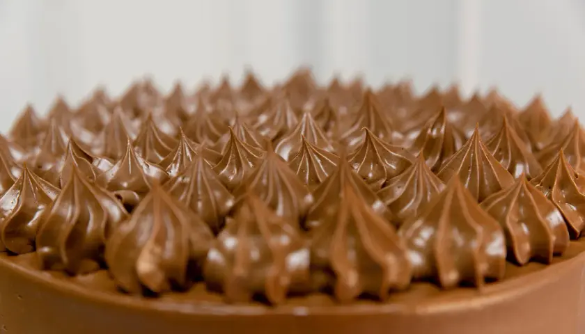 Detalle de una tarta de chocolate con glaseado cremoso, evocando deliciosos sabores de tarta.