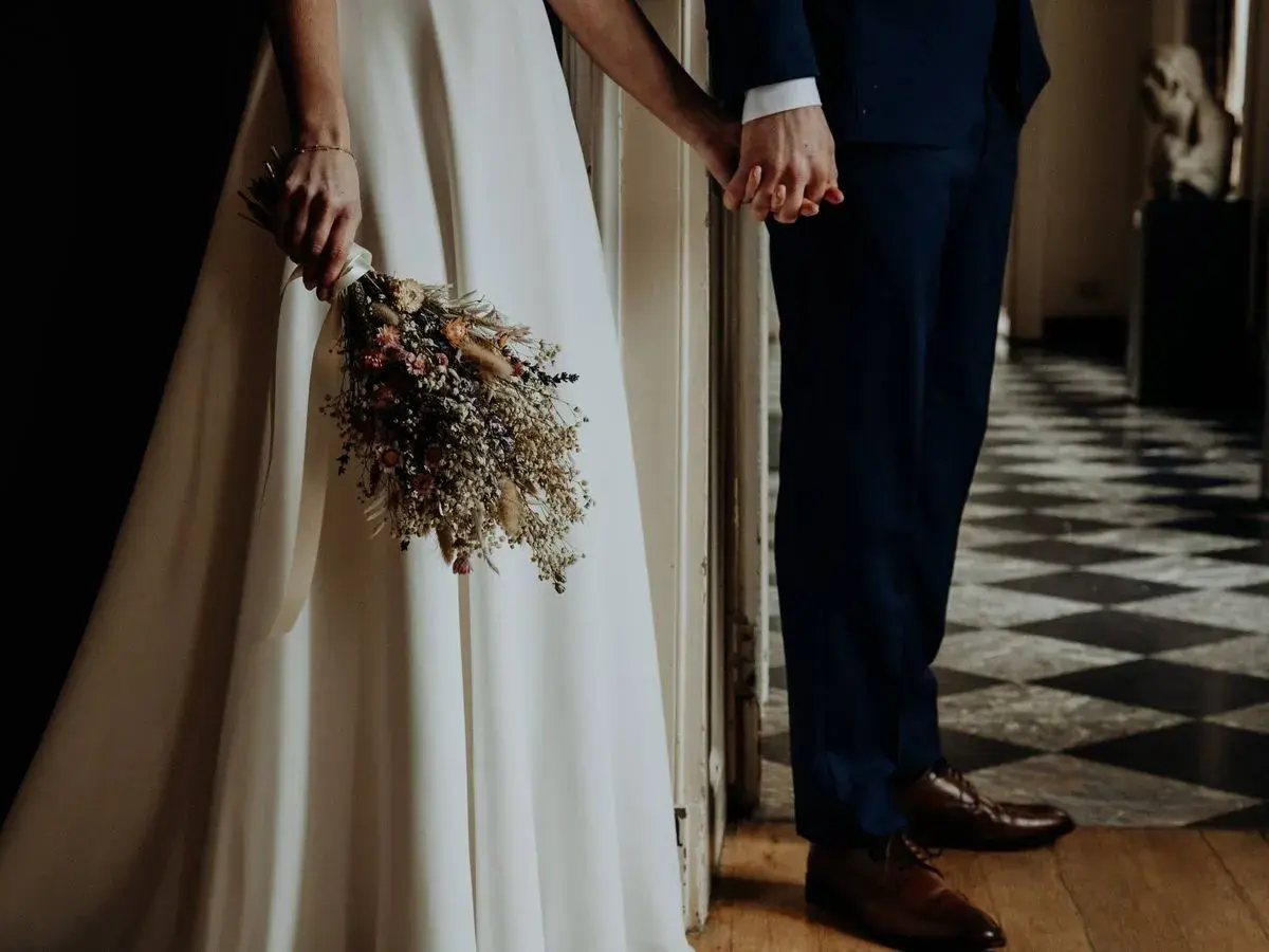 Novios tomados de la mano, ella con un ramo de flores secas, listos para su ceremonia civil.