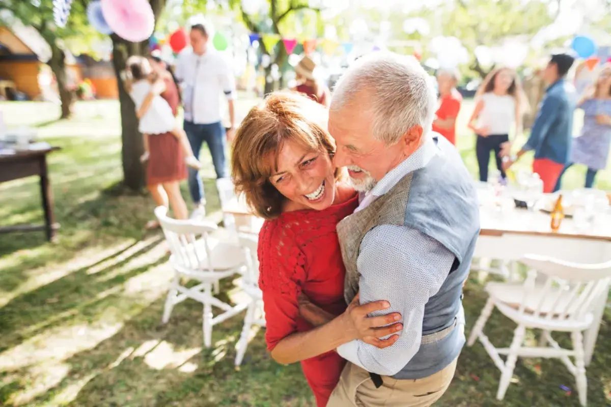 Pareja mayor bailando feliz en una fiesta al aire libre. 30 años de casados que significa: amor, complicidad y alegría compartida.