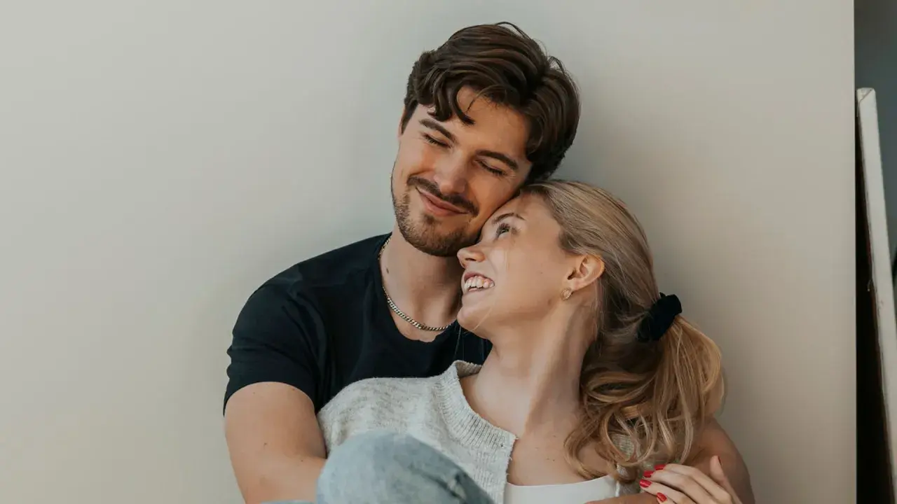 Una pareja joven se abraza tiernamente, sus rostros iluminados por una sonrisa que refleja el amor verdadero.