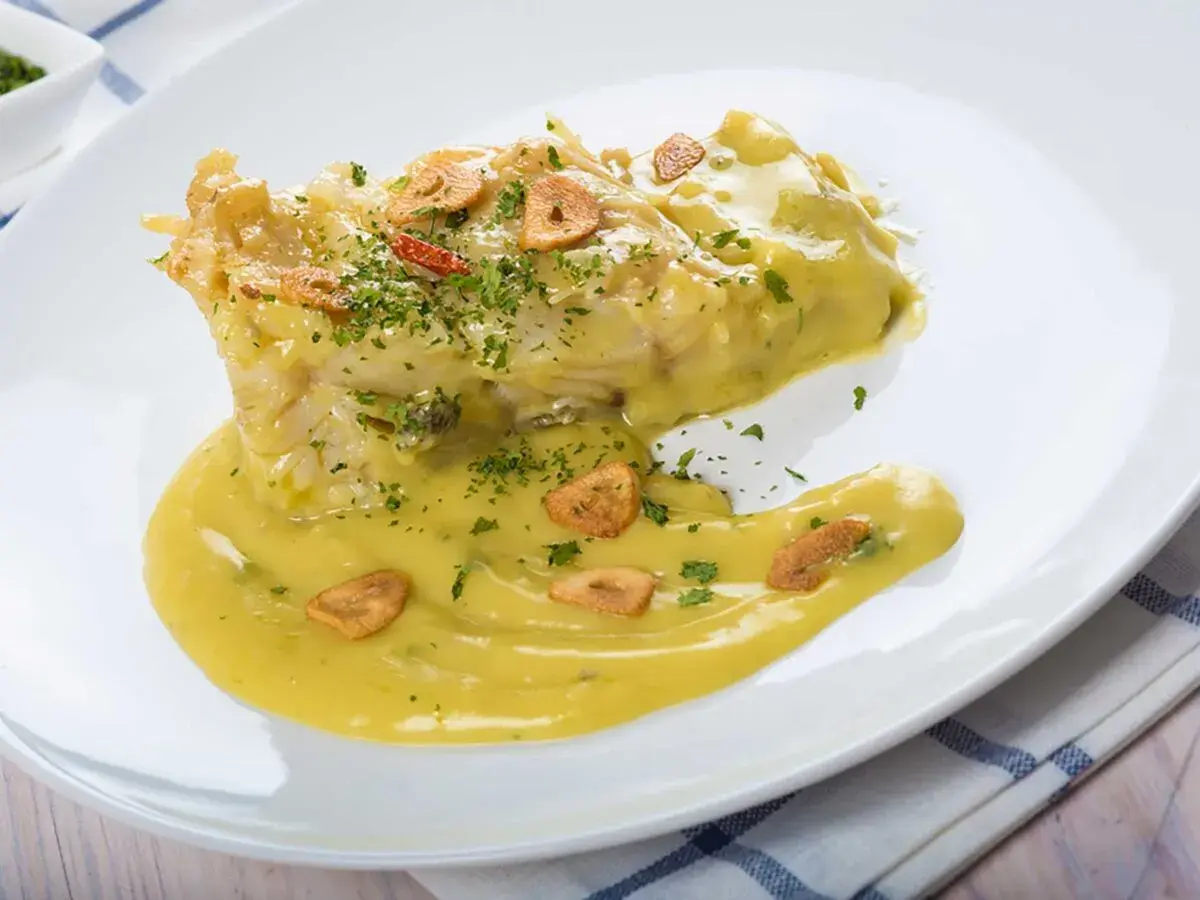 Bacalao en salsa pil pil, con láminas de ajo crujiente y perejil picado. Una deliciosa receta para disfrutar.
