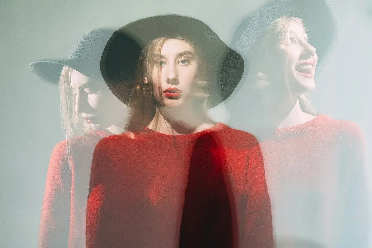 Mujer con sombrero y suéter rojo, capturada en múltiples exposiciones, reflejando su labilidad emocional.