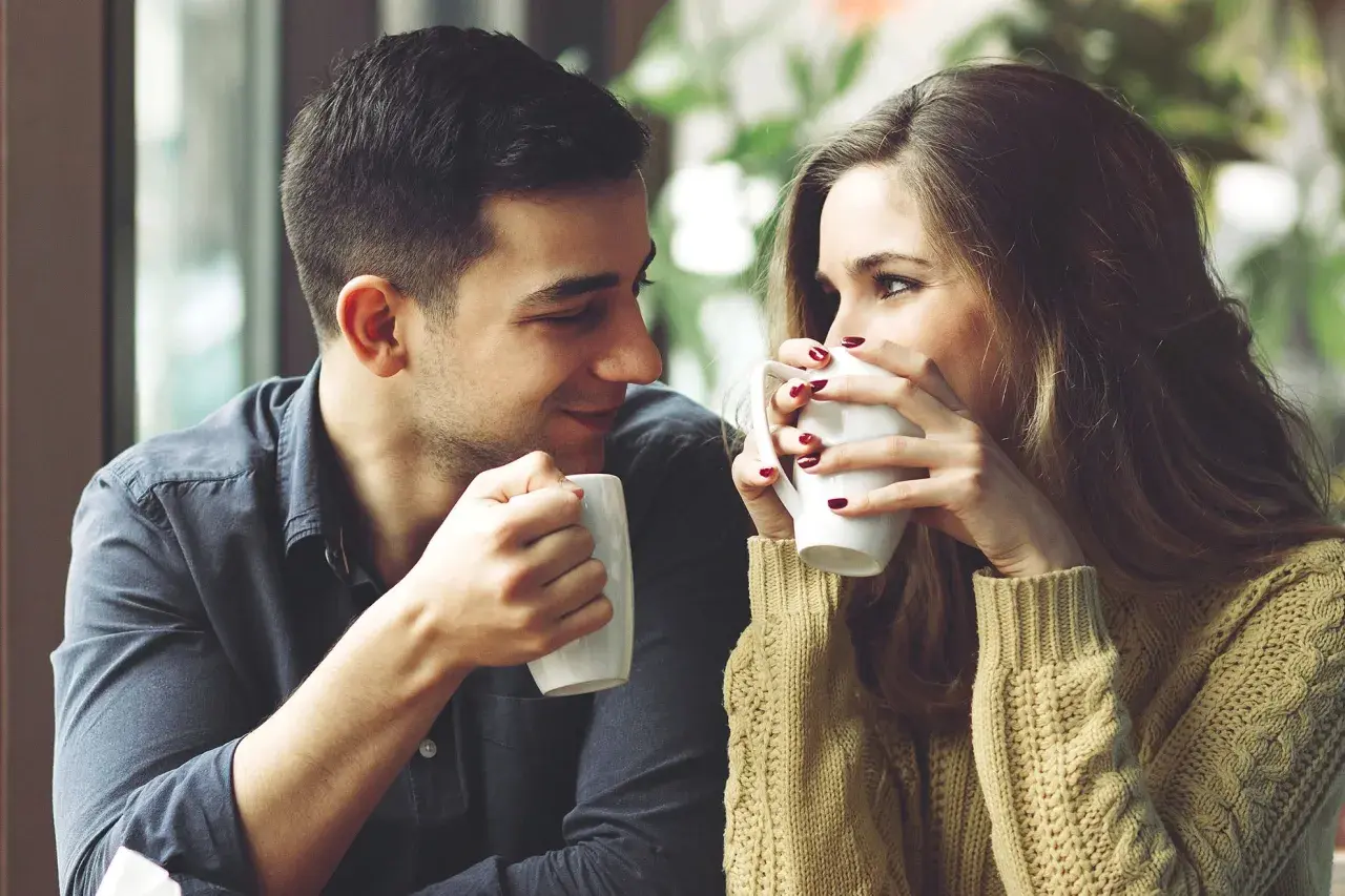 Una pareja joven comparte un café, mirándose con ternura. Un momento perfecto para pensar como decirle a alguien que te gusta.