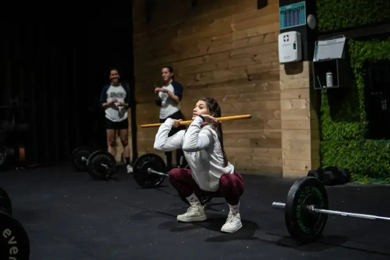 Mujeres entrenando en un gimnasio, demostrando los beneficios del crossfit con una barra.