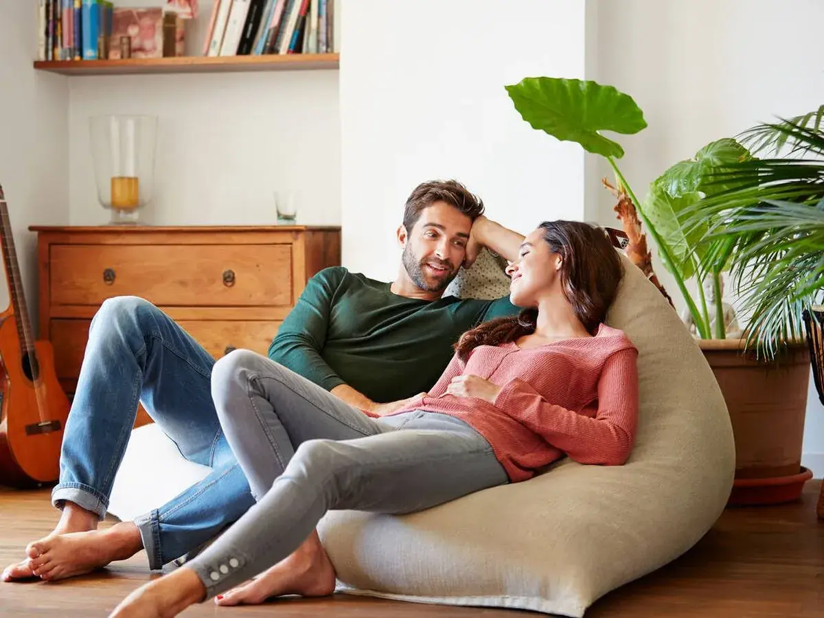 Parejas lat relajadas en un puf, compartiendo un momento íntimo en casa.