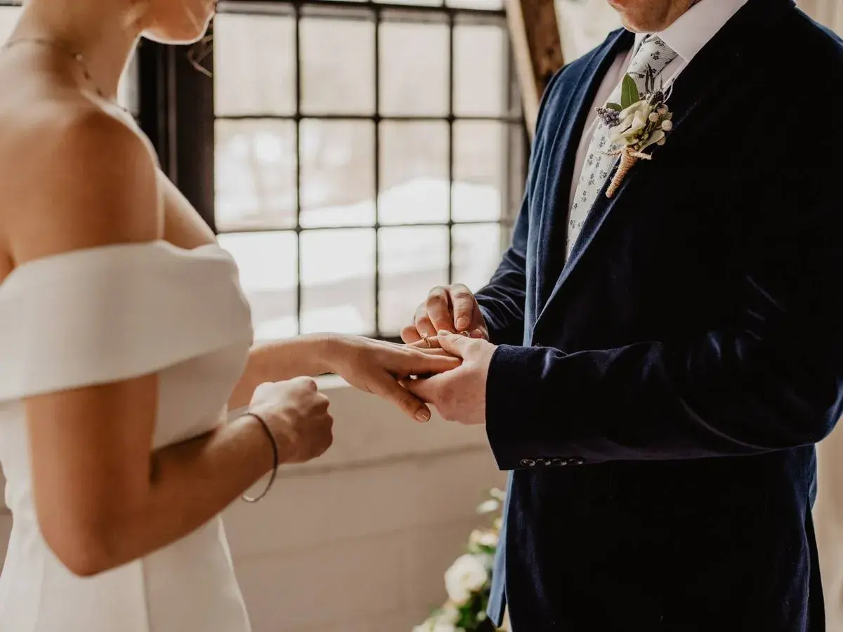 Novio pone anillo a novia. Un juez o funcionario civil es quien puede oficiar una boda civil.