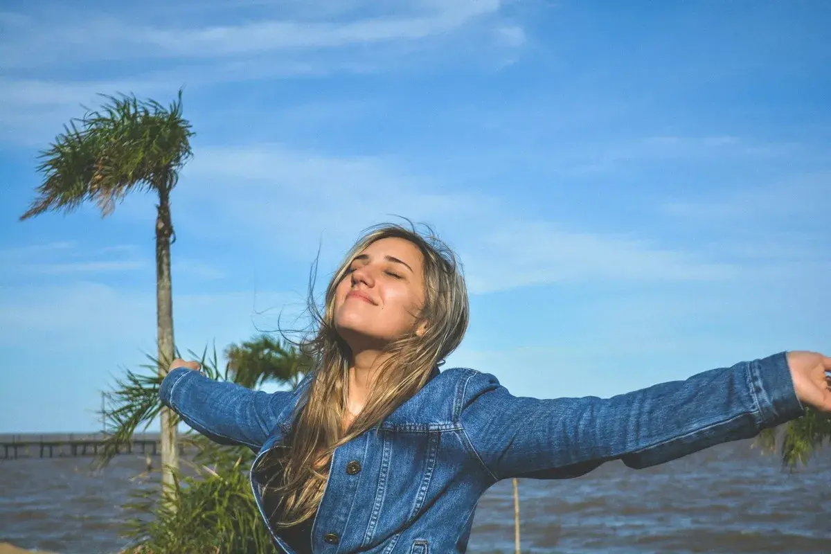 Mujer con brazos extendidos, disfrutando del aire libre, como si viviera una de las frases de Lao Tse sobre la libertad y la naturaleza.