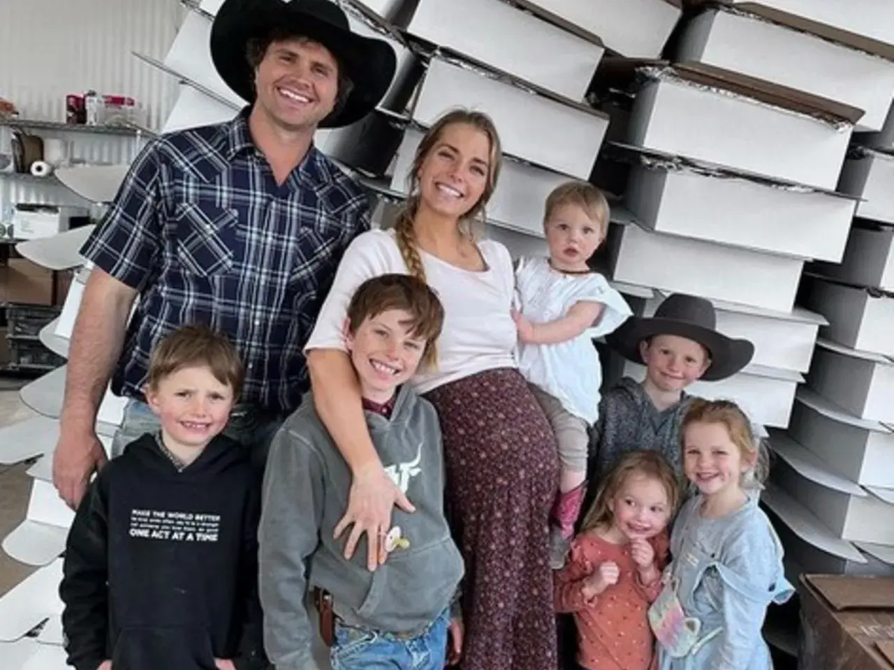 Familia feliz, estilo tradwife que es, posando con sus hijos frente a cajas apiladas.