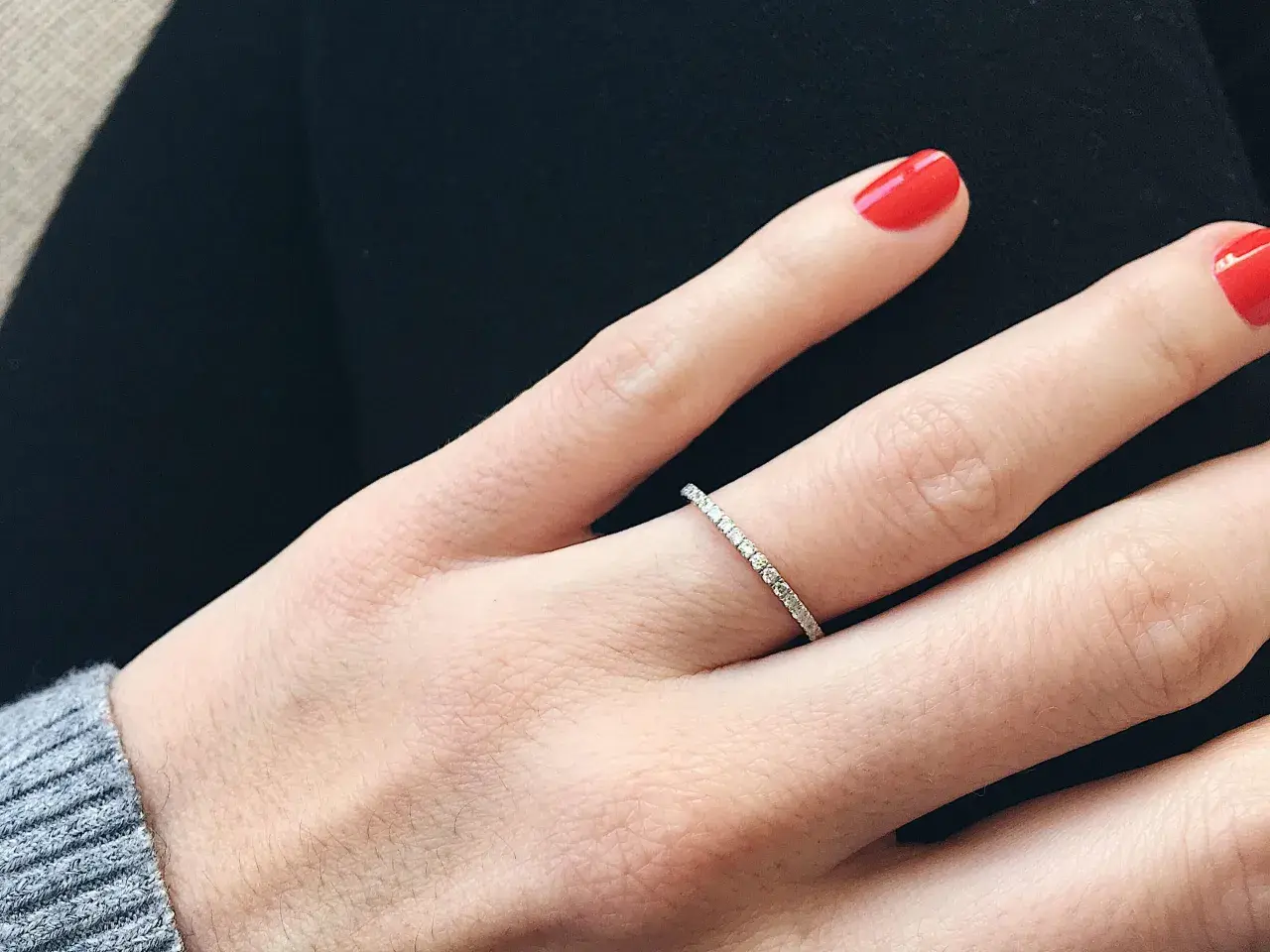 Anillo de diamantes finos, perfecto para frases para alianzas que sellan un amor eterno. Uñas rojas vibrantes.