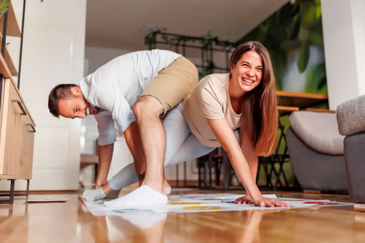 Pareja riendo mientras juega Twister, un divertido juego para jugar en pareja.