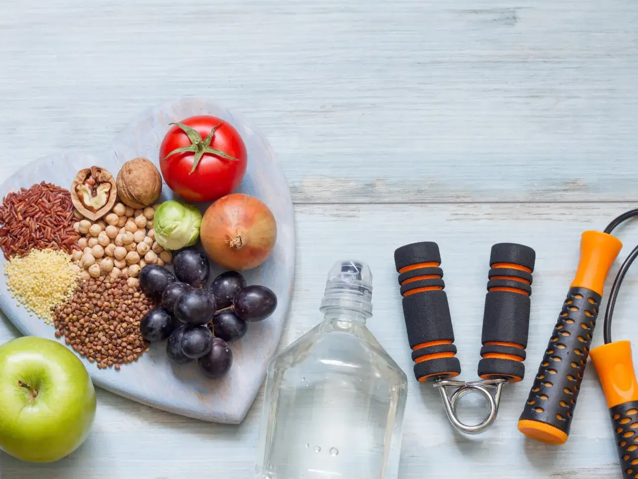 Alimentos saludables y equipo de ejercicio, como una cuerda de saltar y un expansor de mano, para tu motivación personal.