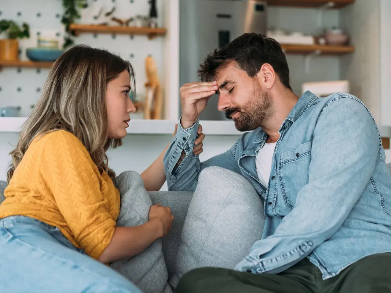 Mujer consuela a su pareja, con la mano en su frente, en un momento de tensión en su vida en pareja.