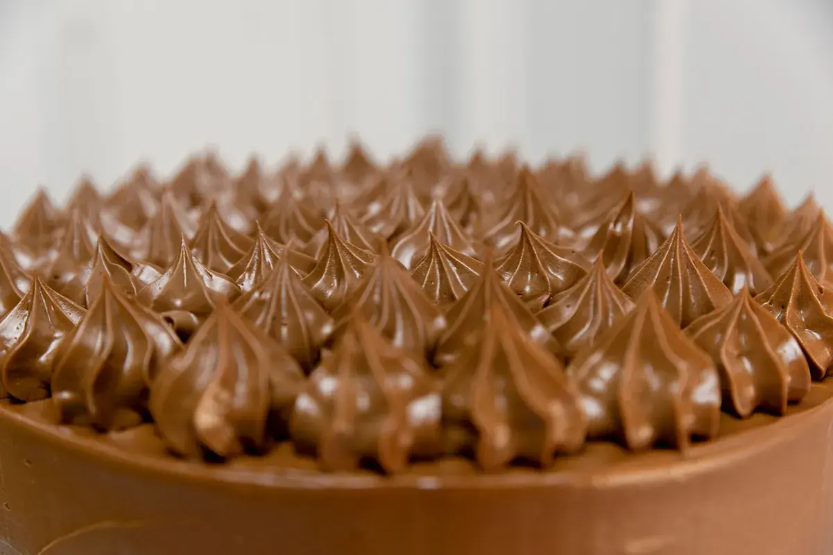 Detalle de una tarta de chocolate con glaseado cremoso, evocando deliciosos sabores de tarta.