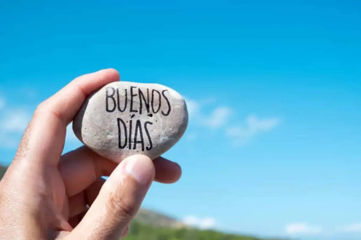 Un cariñoso saludo de buenos días alegres, escrito en una piedra sostenida contra un cielo azul brillante.