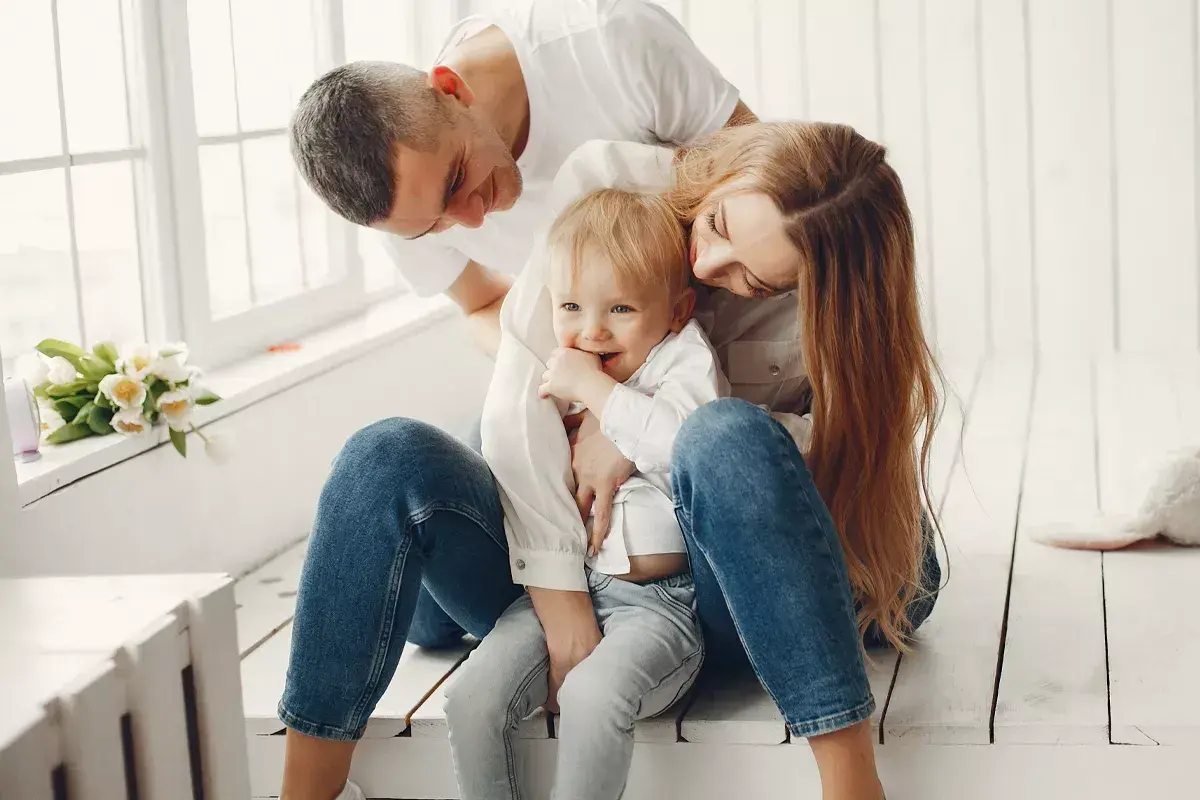 Padres abrazando a su hijo, creando un ambiente de apego seguro. El niño sonríe, rodeado de amor y protección.