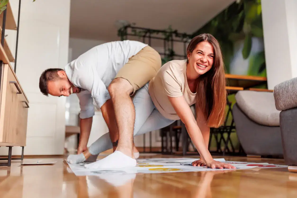 Pareja riendo mientras juega Twister, un divertido juego para jugar en pareja.