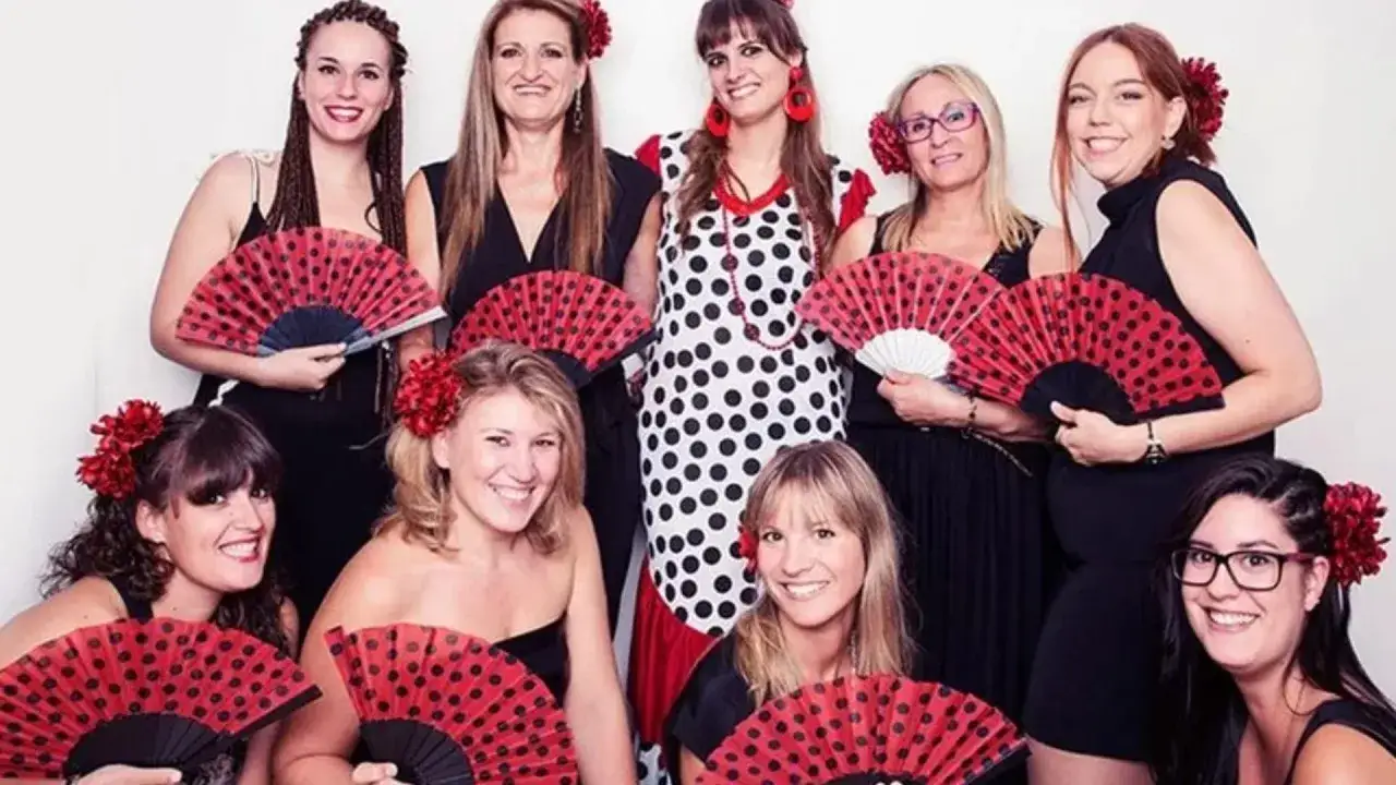 Grupo de mujeres sonrientes con abanicos rojos y negros, celebrando un bridal shower significado.