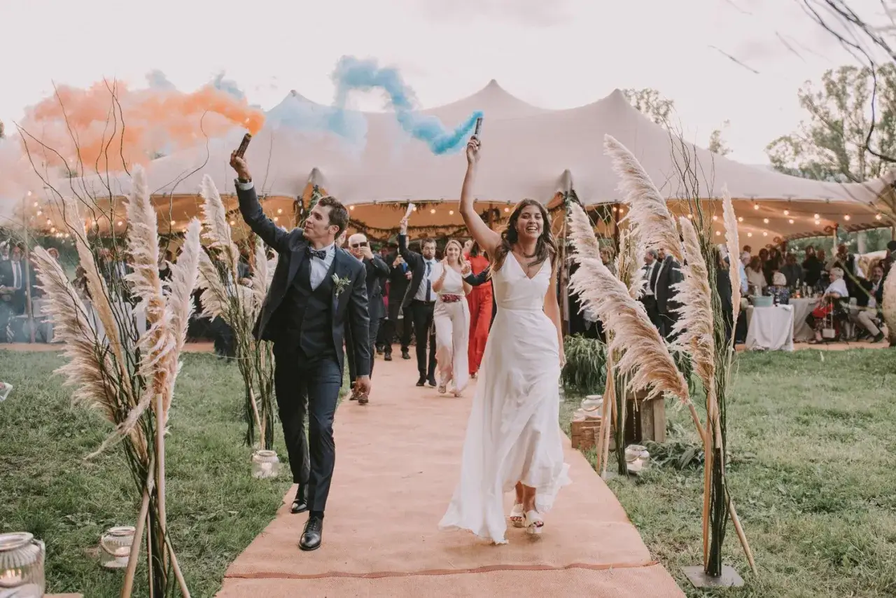 La entrada de los novios al banquete, celebrando con bengalas de humo naranja y azul.
