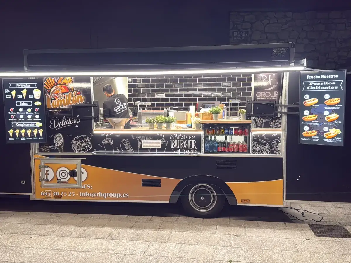 Food trucks iluminados por la noche, uno con el letrero 