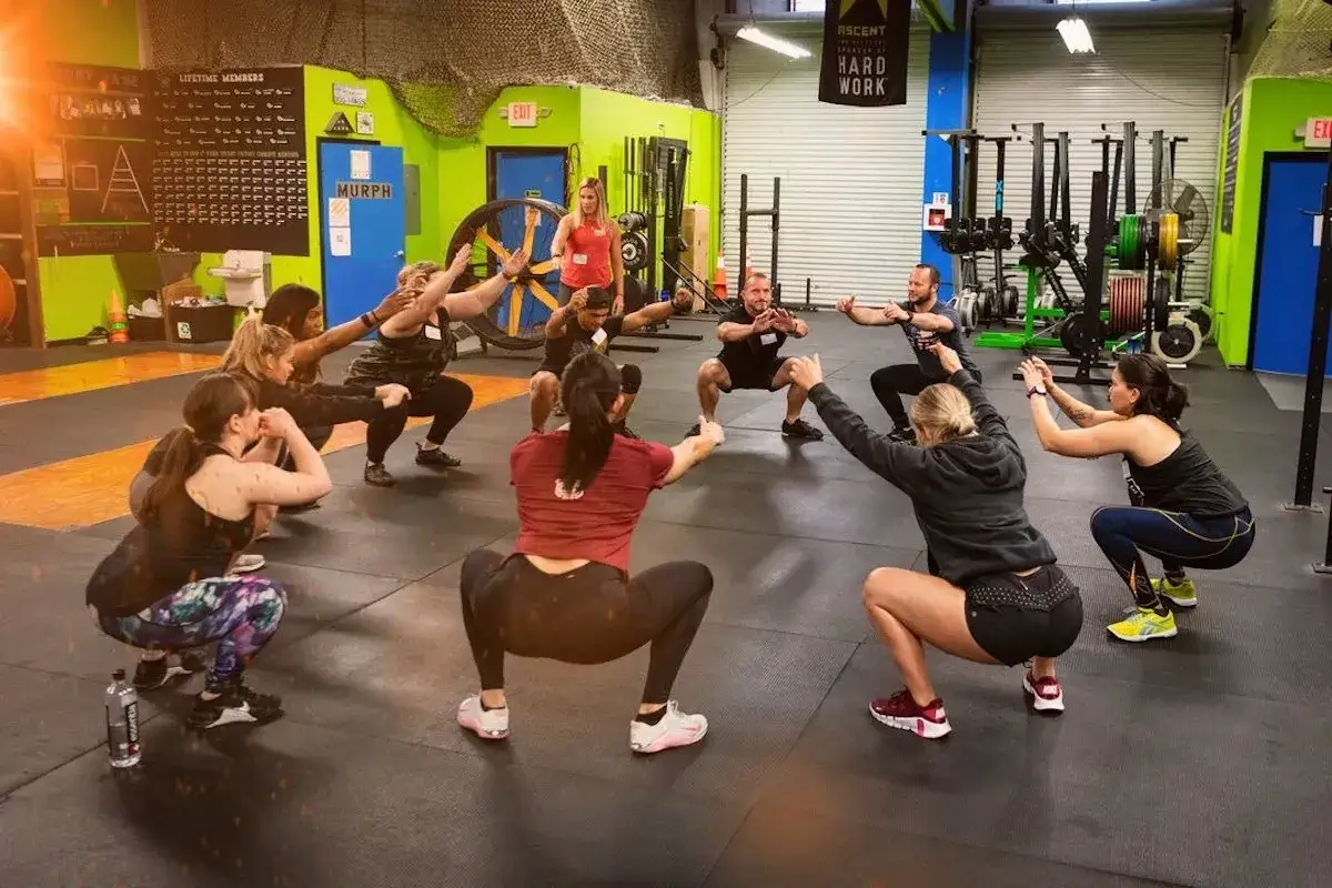 Grupo entrenando sentadillas en un gimnasio, demostrando los beneficios del crossfit para la fuerza y la resistencia.