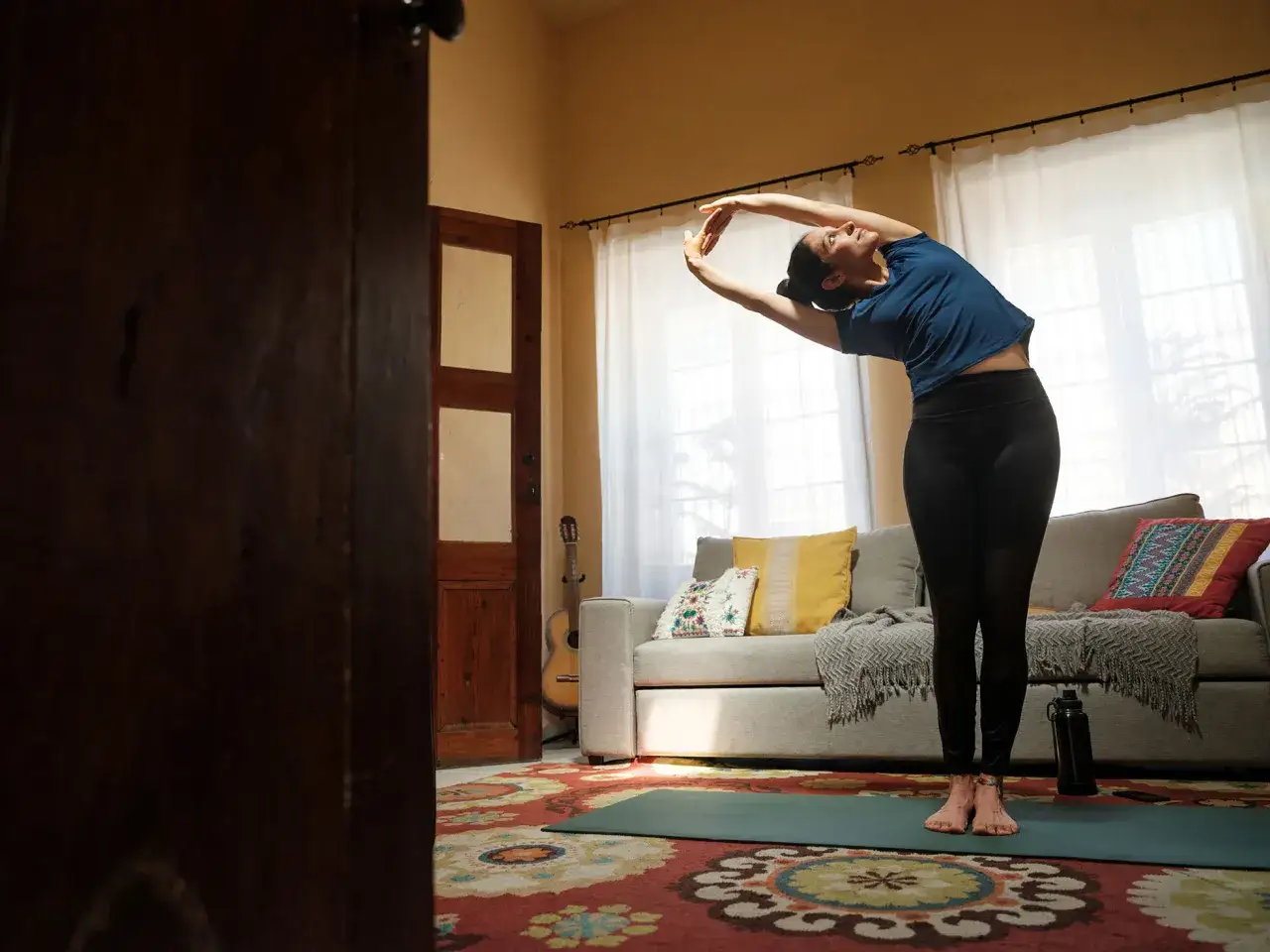 Mujer estirándose en una esterilla, practicando técnicas de relajación en su sala.