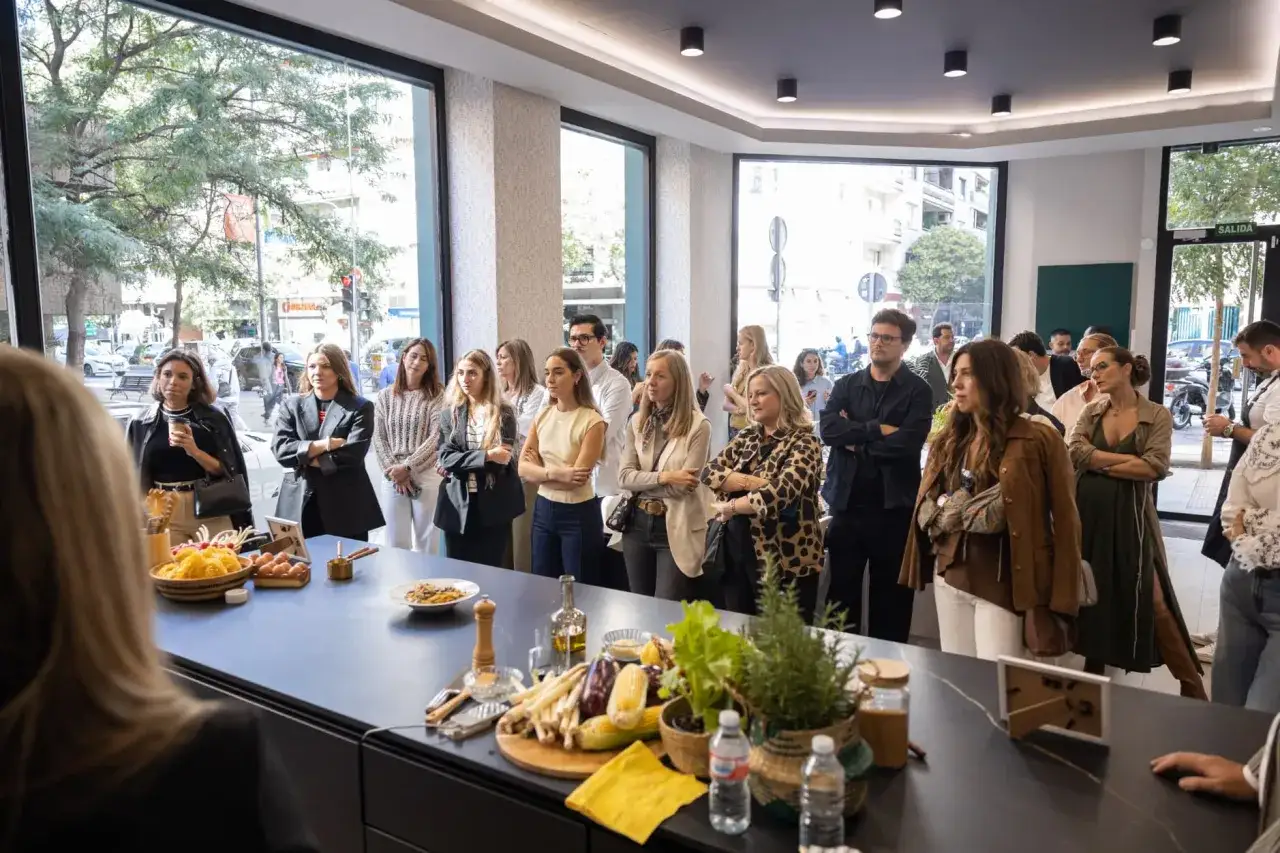 Un grupo de personas observa atentamente una demostraci&oacute;n de cocina. El significado de 